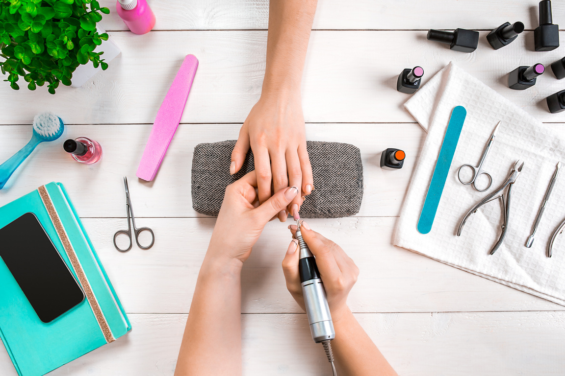Closeup shot of a woman in a nail salon receiving a manicure by a beautician with nail file. Woman getting nail manicure